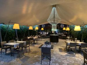 una tenda da pranzo con tavoli, sedie e lampadario pendente di Hotel Naitendì a Cutrofiano