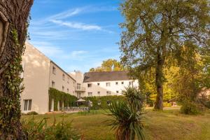 an exterior view of a white building with trees at The Originals Boutique, Parc Hôtel, Orléans Sud in La Chapelle-Saint-Mesmin