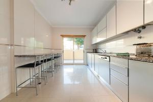 ラゴスにあるC15 - The Patio do Convento Apartmentの白いキャビネットとスツールの列が備わるキッチン