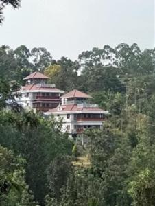 een groep gebouwen op een heuvel met bomen bij Room in Villa - Luxury cottages with beautiful mountain view in Anachal
