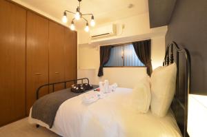 ein Schlafzimmer mit einem Bett mit weißer Bettwäsche und einem Fenster in der Unterkunft River Side Namba 200 in Osaka