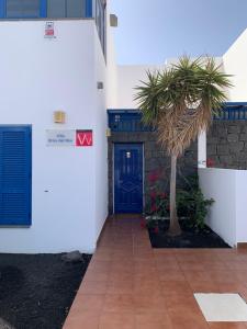 ein Gebäude mit einer blauen Tür und einer Palme in der Unterkunft Villa Brisa del Mar in Playa Blanca