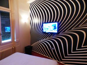 a bedroom with a striped wall with a television on it at Terminus du Forez Saint-Etienne Centre Gare Chateaucreux in Saint-Étienne