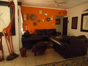 a living room with a black leather couch and a giraffe at Bhangazi Lodge Bed & Breakfast in St Lucia