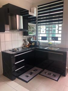 a kitchen with black cabinets and a sink and a stove at SEROJA HOMESTAY in Melaka