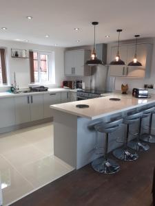 a kitchen with white cabinets and a island with bar stools at 2 Bear Barns in Rhayader