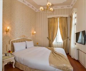 a bedroom with a large white bed with a chandelier at Enderun Hotel Istanbul in Istanbul