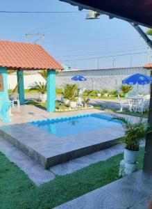 une petite piscine dans une cour avec des parasols dans l'établissement Pousada da Praia, à Itaipuaçu