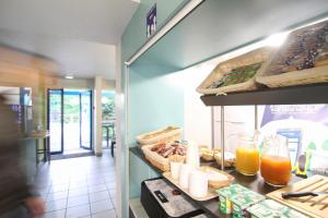 un restaurant avec un comptoir servant de la nourriture et des boissons dans l'établissement Kyriad Direct Poitiers - Gare du Futuroscope, à Chasseneuil-du-Poitou