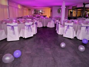 un salón de banquetes con mesas blancas con globos púrpura en Hotel Los Olivos en Getafe