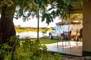 una furgoneta blanca estacionada en un muelle junto a un lago en Zambezi Mubala Campsite en Katima Mulilo
