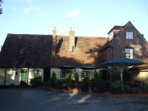 une maison avec un parasol devant elle dans l'établissement Ye Olde George Inn - Badger Pubs, à Privett