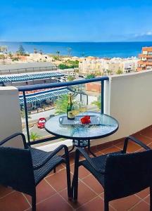 a glass table on a balcony with a view of the beach at Ocean View Elegant Magic Apartment in Palm-Mar