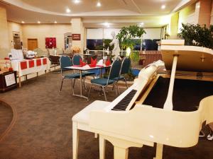 a room with a piano and a table and chairs at Pearl Hotel Jeju in Jeju