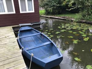 a blue boat parked on a dock next to a house at Houseboat Linquenda in Woubrugge