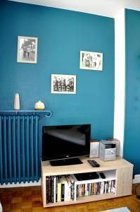 Il comprend un salon doté d'une télévision et d'un mur bleu. dans l'établissement Gite Regard sur l'Horizon, à Bois-Guillaume