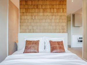 a bedroom with a white bed with two brown pillows at Concorde Silesian Place Apartments in Katowice