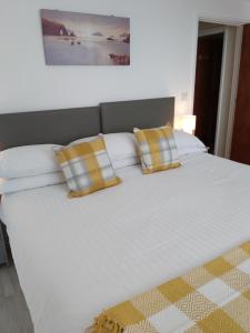 1 cama blanca grande con 2 almohadas amarillas. en Trevarrian Lodge en Newquay