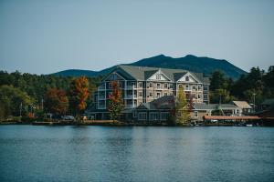 a lake with a house and a boat in front of it at Saranac Waterfront Lodge in Saranac Lake