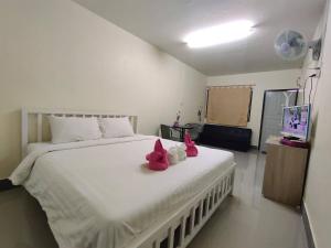 ein Schlafzimmer mit einem weißen Bett mit rosa ausgestopften Tieren in der Unterkunft ทองอุไร โฮมสเตย์ in Mae Sai