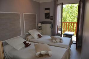 two beds in a room with a balcony at Hotel & Restaurant Le Chalvet in Embrun