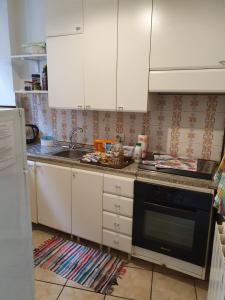 eine Küche mit weißen Schränken, einer Spüle und einem Herd in der Unterkunft Appartamento da Raffaella CIR O12133 CNI OOO39 in Varese