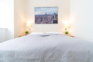 1 dormitorio con 1 cama blanca y una pintura en la pared en Apartment Mandlgasse I contactless check-in, en Viena