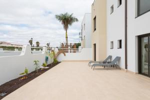 un patio con 2 sillas y un edificio en HomeForGuest Flat with large terrace in modern residential complex with swimming pool, en Caleta de Fuste