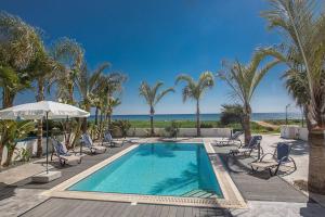 una piscina con sillas, palmeras y el océano en Villa Adaman - Stunning 3 Bedroom Seafront Villa with Pool - Close to the Beach, en Ayia Napa