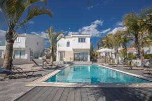 una piscina frente a una casa con palmeras en Villa Adaman - Stunning 3 Bedroom Seafront Villa with Pool - Close to the Beach, en Ayia Napa