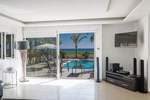 sala de estar con puerta corredera de cristal que da a la piscina en Villa Adaman - Stunning 3 Bedroom Seafront Villa with Pool - Close to the Beach, en Ayia Napa