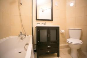 a bathroom with a toilet, bathtub, sink and mirror at Temple Bar District Apartments in Dublin