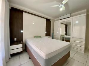 1 dormitorio con 1 cama blanca grande y espejo en Apto 2 dom e 1 quadra do mar edifício Vila Velha Capão da Canoa, en Capão da Canoa