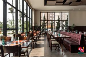 - un restaurant avec des tables, des chaises et de grandes fenêtres dans l'établissement Rio Hotel by Bourbon Curitiba Aeroporto, à São José dos Pinhais