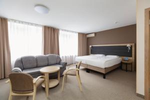 a bedroom with a bed and a couch and a table at AMAKS Park Hotel in Voronezh