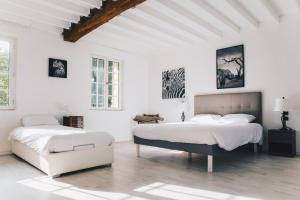 Duas camas num quarto com paredes brancas em Château du Landin - Bains nordiques em Le Landin