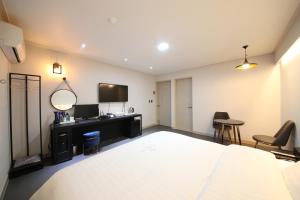 a bedroom with a bed and a tv and chairs at VIP Hotel Mokpo in Mokpo