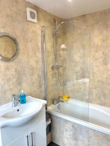Milburn Cottage 2- Luxury Accommodation في Monkwearmouth: حمام مع دش ومغسلة وحوض استحمام