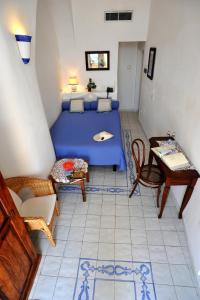 a bedroom with a blue bed and a table and chairs at Hotel La Casa sul Mare in Procida