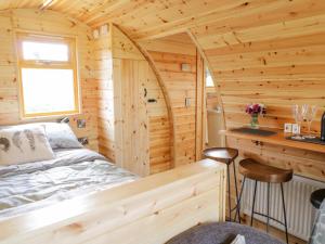 um quarto num chalé de madeira com uma cama e uma secretária em Embden Pod at Banwy Glamping em Welshpool