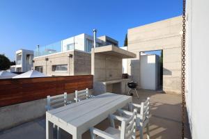 een witte tafel en stoelen op een balkon met een gebouw bij Luxury Cyprus Villa Sky Villa Private Pool Sea View 1 BDR Paphos in Paphos