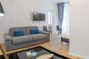 a living room with a gray couch and blue pillows at Logement de charme - Porto Riche - Cœur historique Bordeaux in Bordeaux