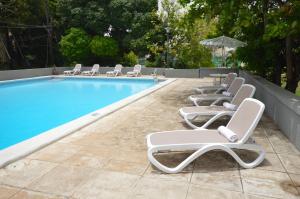 a row of lounge chairs next to a swimming pool at The Liguanea Club in Kingston