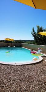 una piscina con un bote de juguete y una sombrilla en La Tranquillite, La Serenite, en Nanteuil-de-Bourzac
