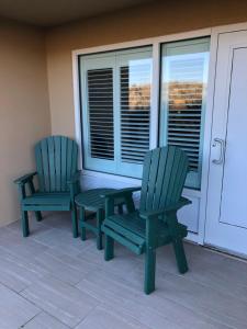 two green chairs and a table on a porch at Shutters on the Banks in Kill Devil Hills