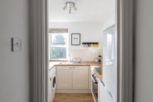een witte keuken met een wastafel en een vaatwasser bij Modern & Spacious 2 Bedroom Maisonette in Bath