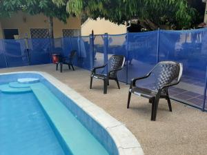3 Stühle und ein Pool neben einem Zaun in der Unterkunft Condominio El Portal Casa 5 in Carmen de Apicalá