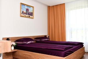 sypialnia z łóżkiem z fioletowymi prześcieradłami i oknem w obiekcie VIP Apartament number 9 w mieście Lublin