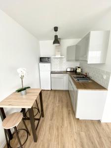 a kitchen with white cabinets and a wooden table at L'INDUSTRIEL CHIC, 2 PIECES AVEC VU IMPRENABLE SUR ROUEN in Rouen