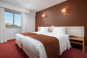 a hotel room with two beds and a window at Hotel Sao Luis in Leiria